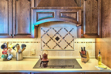 Inredning av ett klassiskt kök, med luckor med upphöjd panel, skåp i mörkt trä, bänkskiva i kvarts, beige stänkskydd, stänkskydd i stenkakel och rostfria vitvaror
