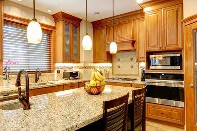 Kitchen - mid-sized traditional l-shaped ceramic tile kitchen idea in Atlanta with an undermount sink, raised-panel cabinets, medium tone wood cabinets, granite countertops, beige backsplash, ceramic backsplash, stainless steel appliances and an island