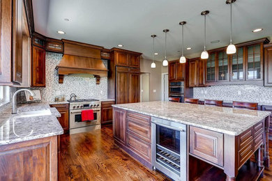 This is an example of a large classic u-shaped kitchen/diner in Denver with a submerged sink, raised-panel cabinets, dark wood cabinets, granite worktops, multi-coloured splashback, glass tiled splashback, integrated appliances, medium hardwood flooring, an island and brown floors.