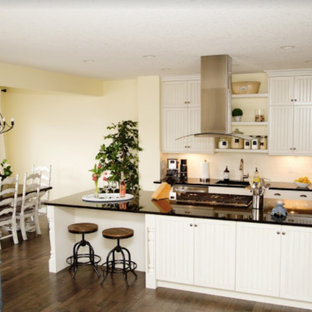 Photo of a mid-sized transitional single-wall open plan kitchen in Calgary with an undermount sink, louvered cabinets, white cabinets, solid surface benchtops, white splashback, subway tile splashback, stainless steel appliances, laminate floors, with island and brown floor.
