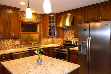 Mid-sized elegant l-shaped cement tile floor and brown floor enclosed kitchen photo in Indianapolis with a double-bowl sink, raised-panel cabinets, medium tone wood cabinets, granite countertops, beige backsplash, mosaic tile backsplash, stainless steel appliances and an island