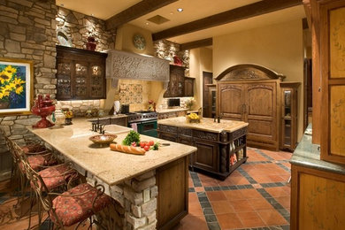 Large mediterranean u-shaped kitchen in Phoenix with a built-in sink, glass-front cabinets, dark wood cabinets, granite worktops, stainless steel appliances, terracotta flooring, an island and multi-coloured floors.