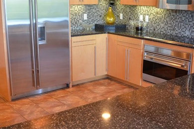 Example of a mid-sized trendy l-shaped terra-cotta tile enclosed kitchen design in Minneapolis with an undermount sink, flat-panel cabinets, medium tone wood cabinets, granite countertops, multicolored backsplash, mosaic tile backsplash, stainless steel appliances and an island