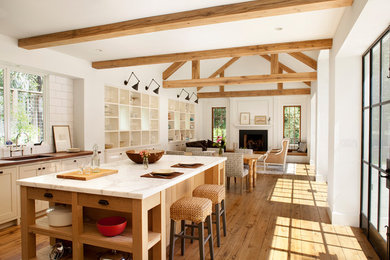 Exempel på ett stort lantligt vit linjärt vitt kök med öppen planlösning, med en undermonterad diskho, skåp i shakerstil, vita skåp, marmorbänkskiva, vitt stänkskydd, stänkskydd i tunnelbanekakel, ljust trägolv, en köksö och brunt golv
