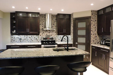 Example of a mid-sized minimalist u-shaped ceramic tile enclosed kitchen design in Calgary with recessed-panel cabinets, dark wood cabinets, granite countertops, multicolored backsplash, glass tile backsplash, stainless steel appliances and an island