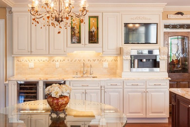 Example of a large classic medium tone wood floor and brown floor enclosed kitchen design in Other with an undermount sink, raised-panel cabinets, white cabinets, marble countertops, beige backsplash, ceramic backsplash, stainless steel appliances, an island and multicolored countertops