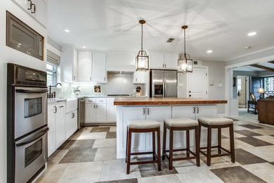 Inspiration for a timeless ceramic tile kitchen remodel in Dallas with a farmhouse sink, white cabinets, granite countertops, gray backsplash, subway tile backsplash, stainless steel appliances and an island