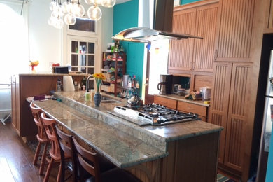 Eat-in kitchen - mid-sized eclectic l-shaped medium tone wood floor eat-in kitchen idea in New Orleans with an island, beaded inset cabinets, medium tone wood cabinets, stainless steel appliances, an undermount sink and granite countertops