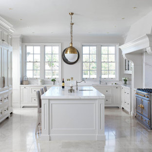 This is an example of a large traditional u-shaped open plan kitchen in Other with a drop-in sink, beaded inset cabinets, white cabinets, marble benchtops, white splashback, marble splashback, stainless steel appliances, porcelain floors, with island, beige floor and yellow benchtop.