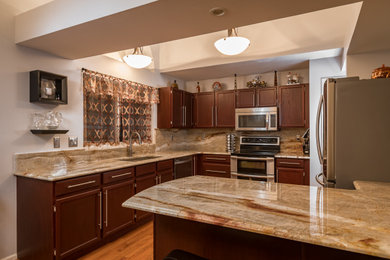 Example of a mid-sized classic light wood floor eat-in kitchen design in St Louis with an undermount sink, recessed-panel cabinets, dark wood cabinets, quartzite countertops, multicolored backsplash, stainless steel appliances, a peninsula and multicolored countertops