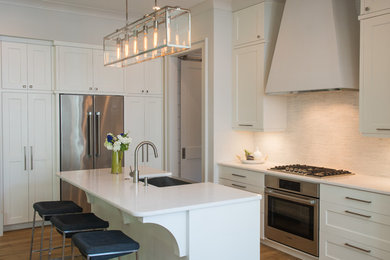 Example of a transitional dark wood floor kitchen design in Charleston with a farmhouse sink, shaker cabinets, white cabinets, white backsplash, stainless steel appliances and an island
