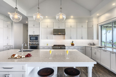 Example of a transitional dark wood floor and brown floor kitchen design in Hawaii with a single-bowl sink, shaker cabinets, white cabinets, granite countertops, white backsplash, subway tile backsplash, stainless steel appliances and an island