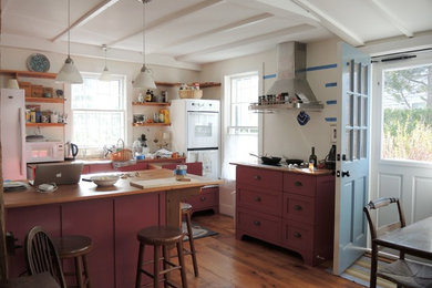 Cette image montre une cuisine américaine linéaire traditionnelle de taille moyenne avec un placard à porte shaker, des portes de placard rouges, un plan de travail en bois et îlot.