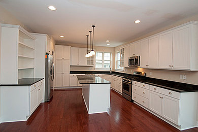 Example of a mid-sized farmhouse u-shaped medium tone wood floor eat-in kitchen design in Detroit with an undermount sink, recessed-panel cabinets, white cabinets, granite countertops, stainless steel appliances and an island