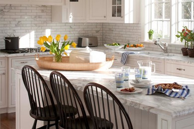 Eat-in kitchen - mid-sized traditional l-shaped dark wood floor eat-in kitchen idea in Boston with marble countertops, an undermount sink, shaker cabinets, white cabinets, white backsplash, stainless steel appliances and an island