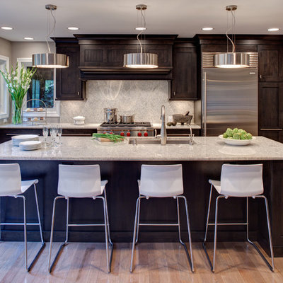 Kitchen - contemporary galley kitchen idea in Chicago with stainless steel appliances, an undermount sink, recessed-panel cabinets, dark wood cabinets, white backsplash and stone slab backsplash