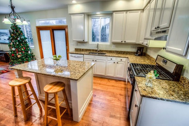 Example of a mid-sized classic l-shaped medium tone wood floor kitchen design in Chicago with a double-bowl sink, white cabinets, granite countertops, stainless steel appliances and an island