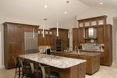 Trendy l-shaped eat-in kitchen photo in Miami with an undermount sink, shaker cabinets, medium tone wood cabinets, granite countertops, gray backsplash, stone slab backsplash and stainless steel appliances
