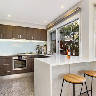 Photo of a contemporary u-shaped open plan kitchen in Sydney with brown cabinets, quartz benchtops, white splashback, porcelain splashback, stainless steel appliances, terrazzo floors, grey floor, white benchtop, an undermount sink, flat-panel cabinets and a peninsula.