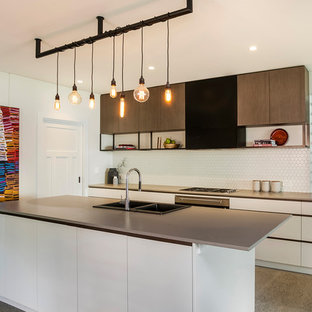 Inspiration for a mid-sized contemporary galley kitchen in Sydney with white splashback, with island, a drop-in sink, flat-panel cabinets, white cabinets, grey floor and grey benchtop.