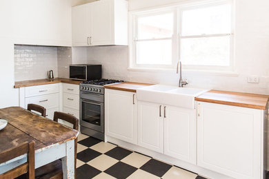 キャンベラにある高級な小さなラスティックスタイルのおしゃれなキッチン (エプロンフロントシンク、白いキャビネット、木材カウンター、白いキッチンパネル、サブウェイタイルのキッチンパネル) の写真