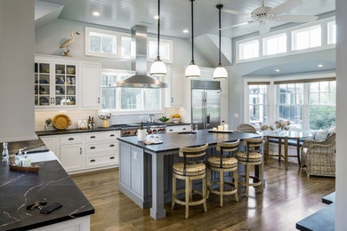 Example of a large transitional l-shaped medium tone wood floor kitchen design in New York with a farmhouse sink, beaded inset cabinets, white cabinets, soapstone countertops, blue backsplash, subway tile backsplash, stainless steel appliances and an island