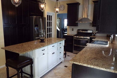 Example of a mid-sized transitional limestone floor eat-in kitchen design in Philadelphia with a farmhouse sink, shaker cabinets, dark wood cabinets, granite countertops, white backsplash, subway tile backsplash, stainless steel appliances and an island