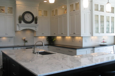 Large classic l-shaped kitchen/diner in Indianapolis with a submerged sink, recessed-panel cabinets, white cabinets, laminate countertops, white splashback, ceramic splashback, stainless steel appliances, dark hardwood flooring and an island.
