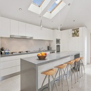 Foto di una cucina design di medie dimensioni con lavello a doppia vasca, ante con bugna sagomata, ante bianche, top alla veneziana, paraspruzzi beige, paraspruzzi in lastra di pietra, elettrodomestici in acciaio inossidabile, pavimento alla veneziana, pavimento grigio e top grigio