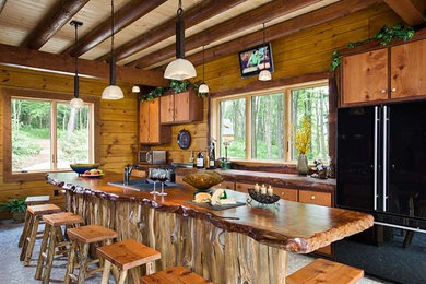 Aménagement d'une grande cuisine américaine montagne en bois brun avec un évier 2 bacs, un placard à porte plane, un plan de travail en bois, un sol en calcaire et îlot.