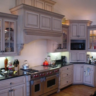 Mid-sized traditional l-shaped open plan kitchen in Charlotte with raised-panel cabinets, beige cabinets, granite benchtops, stainless steel appliances, light hardwood floors and with island.
