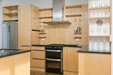 Photo of a medium sized modern l-shaped open plan kitchen in Other with light wood cabinets, granite worktops, glass sheet splashback, stainless steel appliances, an island and black worktops.