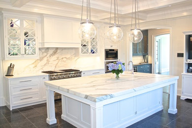 Example of a huge classic u-shaped ceramic tile enclosed kitchen design in Los Angeles with a farmhouse sink, shaker cabinets, white cabinets, marble countertops, stone slab backsplash, stainless steel appliances and an island