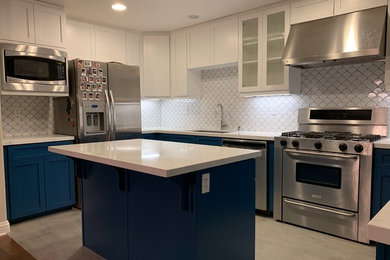 Inspiration for a mid-sized transitional u-shaped cement tile floor and gray floor kitchen remodel in San Diego with an undermount sink, shaker cabinets, blue cabinets, quartz countertops, white backsplash, ceramic backsplash, stainless steel appliances, an island and white countertops