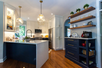 Inspiration for a large transitional u-shaped medium tone wood floor and brown floor eat-in kitchen remodel in Toronto with an undermount sink, shaker cabinets, white cabinets, quartz countertops, white backsplash, ceramic backsplash, stainless steel appliances, a peninsula and white countertops