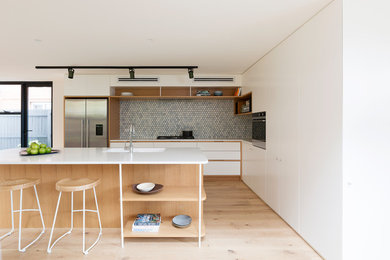 Ejemplo de cocina contemporánea de tamaño medio con suelo de madera clara, una isla, suelo marrón y encimeras blancas