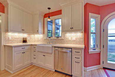 Inspiration for a mid-sized mediterranean galley medium tone wood floor enclosed kitchen remodel in Portland with a farmhouse sink, beaded inset cabinets, white cabinets, quartz countertops and terra-cotta backsplash