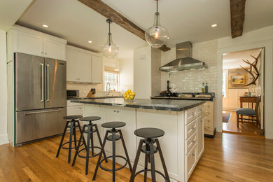 Eat-in kitchen - mid-sized transitional u-shaped medium tone wood floor eat-in kitchen idea in Boston with an undermount sink, shaker cabinets, white cabinets, soapstone countertops, white backsplash, ceramic backsplash, stainless steel appliances and an island