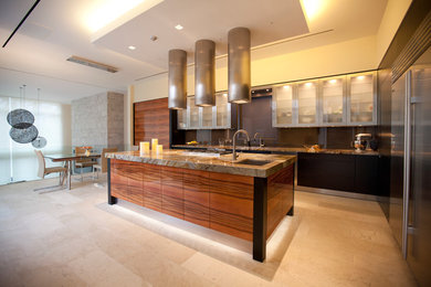 Eat-in kitchen - large l-shaped travertine floor eat-in kitchen idea in Dallas with a double-bowl sink, glass-front cabinets, stainless steel cabinets, marble countertops, stainless steel appliances and an island