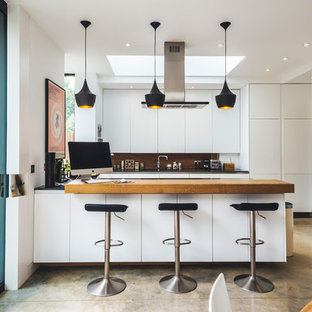Design ideas for a medium sized contemporary u-shaped kitchen/diner in London with flat-panel cabinets, white cabinets, wood worktops, brown splashback, wood splashback, black appliances, a breakfast bar and beige worktops.