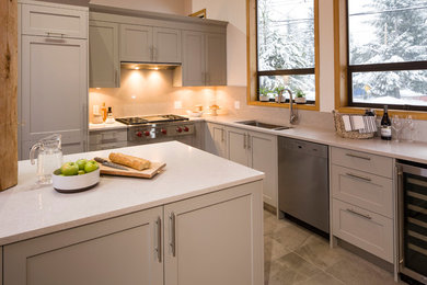 Inspiration for a mid-sized transitional l-shaped ceramic tile eat-in kitchen remodel in Vancouver with an undermount sink, shaker cabinets, gray cabinets, quartz countertops, gray backsplash, stainless steel appliances and an island