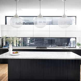 This is an example of a large contemporary l-shaped kitchen in Sydney with an undermount sink, marble benchtops, window splashback, light hardwood floors, with island, grey benchtop, flat-panel cabinets, black cabinets, stainless steel appliances and beige floor.