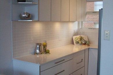 Bild på ett litet funkis kök, med en enkel diskho, vita skåp, bänkskiva i kvarts, vitt stänkskydd, stänkskydd i tunnelbanekakel, rostfria vitvaror och klinkergolv i keramik