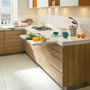 Kleine Moderne Küche in L-Form mit Waschbecken, Küchenrückwand in Weiß, Glasrückwand, Küchengeräten aus Edelstahl, Keramikboden und hellen Holzschränken in London