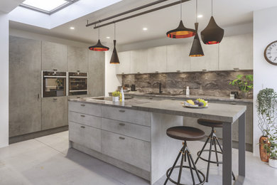 Design ideas for a medium sized contemporary l-shaped open plan kitchen in Oxfordshire with a single-bowl sink, flat-panel cabinets, distressed cabinets, wood worktops, grey splashback, slate splashback, stainless steel appliances, concrete flooring, an island, grey floors and grey worktops.