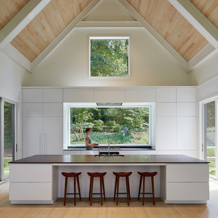 Ispirazione per una cucina costiera con lavello sottopiano, ante lisce, ante bianche, paraspruzzi a finestra, parquet chiaro, isola e pavimento beige