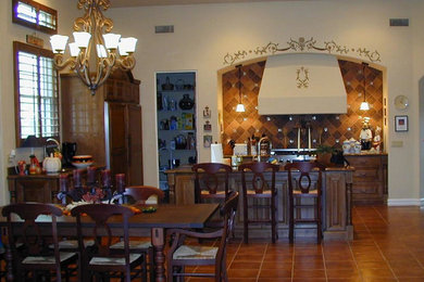 Example of a mid-sized tuscan l-shaped terra-cotta tile open concept kitchen design in Phoenix with raised-panel cabinets, dark wood cabinets, granite countertops, brown backsplash, stone tile backsplash, paneled appliances and an island