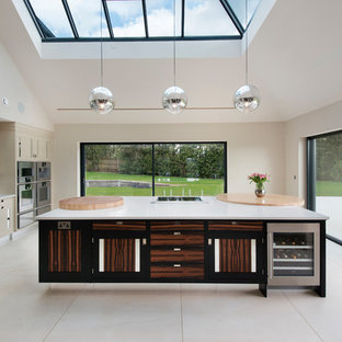 Large contemporary single-wall kitchen in Dorset with a submerged sink, flat-panel cabinets, metallic splashback, mirror splashback, an island and white worktops.