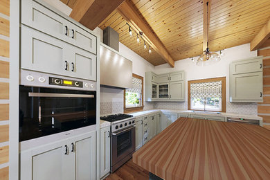Ejemplo de cocina comedor actual con armarios estilo shaker, puertas de armario verdes, encimera de granito, salpicadero blanco, suelo de madera en tonos medios y una isla