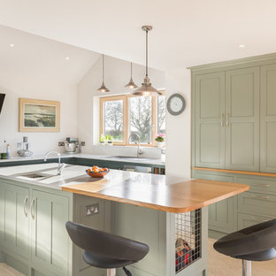 Inspiration for a beach style l-shaped kitchen in Other with a built-in sink, shaker cabinets, green cabinets, white splashback, an island, beige floors and white worktops.